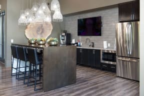 a kitchen with stainless steel appliances and a bar with chairs