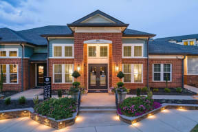 the front of a brick house with a driveway and landscaping