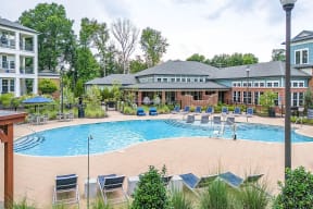 a swimming pool with chairs and a building in the background
