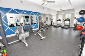 a spacious fitness room with cardio equipment and weights