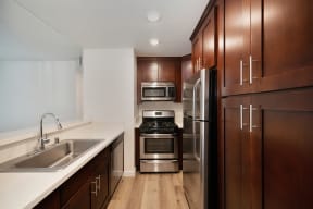 a kitchen with wooden cabinets and stainless steel appliances at Croft Plaza Apartments, West Hollywood, CA 90069