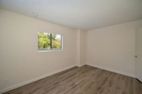 a bedroom with a large window and hardwood floors at Croft Plaza Apartments, West Hollywood, 90069