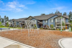 Climbing Area with Wood Chip Floor, Climbing Aparatus, and Blue Apartment Exteriors
