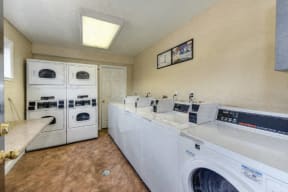 Community Laundry Room with Washers and Dryers, Hardwood Inspired Floors and Ceiling Light at Olympus Park Apartments, Roseville, CA, 95661
