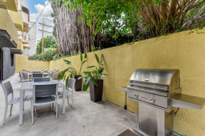 Community BBQ Area with Grill, Picnic Tables, Yellow Wall and Cement Floor at Croft Plaza Apartments, West Hollywood, 90069