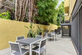 Community BBQ Area with Grill, Picnic Tables, Yellow Wall and Cement Floor at Croft Plaza Apartments, West Hollywood, CA