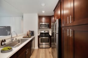 a kitchen with wooden cabinets and stainless steel appliances at Croft Plaza Apartments, West Hollywood California