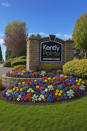 A sign for Kently Pointe Apartment Homes is surrounded by flowers.