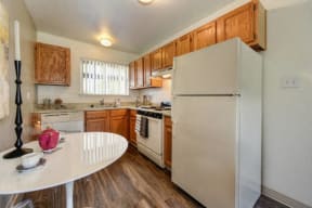 Kitchen with Hardwood Inspired Floors, White Table and Refrigerator at Olympus Park Apartments, Roseville, CA