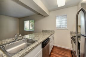 Kitchen with Wood Inspired Floors, Dishwasher and Sink at Hidden Oaks Apartments, Citrus Heights, CA, 95621