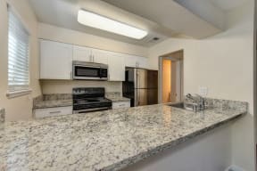 Kitchen with Granite Counters, Ceiling Light, Oven and White Cabinets at Hidden Oaks Apartments, Citrus Heights, CA