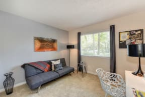 Living Room with Large Window, Carpet, and Black Sofa at Hidden Oaks Apartments, California, 95610