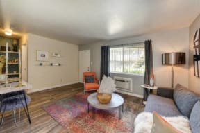 Living Room with Hardwood Inspired Floors, Orange Chairs and Window at Olympus Park Apartments, Roseville, CA