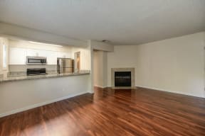 Living Room with View of Kitchen, Hardwood Inspired Floors, and Window at Hidden Oaks Apartments, California