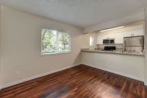 Living Room with View of Kitchen, Hardwood Inspired Floors, and Window at Hidden Oaks Apartments, California, 95610
