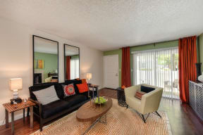 Living Room with Hardwood Inspired Floors, Black Sofa and Mirrors at Hidden Oaks Apartments, Citrus Heights, CA