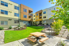 Community Open Green Spaces, with picnic bench and table with walkways around community and  Apartment buildings surrounding the courtyard area.