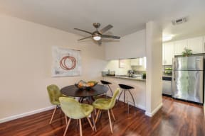Model home dining area with a ceiling fan over the table.  Area has an open concept feel where you can view kitchen from the dining area. at Monte Bello Apartments, California, 95826