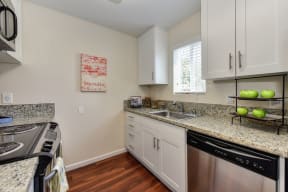 Kitchen with Granite Counters, white cabinets, window above the sink area and stainless dishwasher at Monte Bello Apartments, Sacramento, CA, 95826