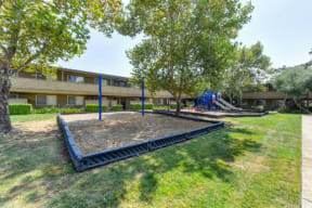 Community Outdoor Playground with Slides, Woodchip Floor and Grass  at Olympus Park Apartments, Roseville, CA