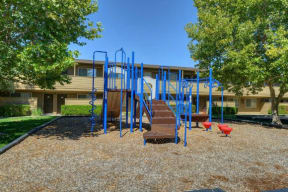 Outdoor Playground with Jungle Gym, Wood Chip Ground, Grass and Trees  at Olympus Park Apartments, Roseville, CA