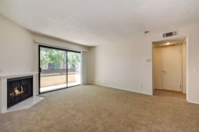 Vacant apartment home living room with carpeting, fireplace and sliding glass door leading to the second floor balcony