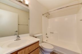 Apartment bathroom with tub/shower, sink and mirror.