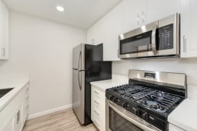 a kitchen with white cabinets and stainless steel appliances and a refrigerator