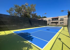 Community Tennis court painted blue and green.  Court is fenced and with lights.