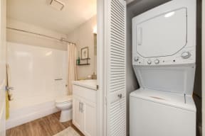 a bathroom with a washer and dryer next to a toilet and a sink