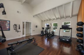 a home gym with a vaulted ceiling and hardwood flooring