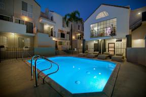 A swimming pool in a backyard at night.