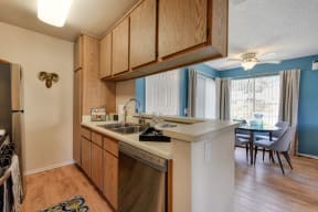 Model home kitchen with views of the dining area in the distance.  There are hardwood inspired flooring through out and large windows allowing for natural sunlight. 