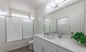 A white bathroom with a toilet, sink, and mirror.