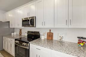 Modern kitchen with white cabinets and granite countertops at The Courts at Maverick Yards Apartments, Mauldin, SC 29662