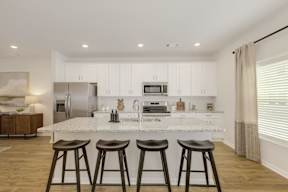 White kitchen with breakfast bar and bar stools at The Courts at Maverick Yards Apartments, Mauldin
