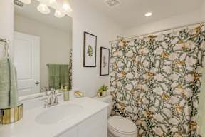 Bathroom with botanical shower curtain and framed leaf art at The Courts at Maverick Yards Apartments, South Carolina