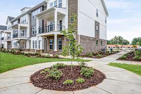 Brick townhomes with covered balconies and tree lined walkways at The Courts at Maverick Yards Apartments, South Carolina