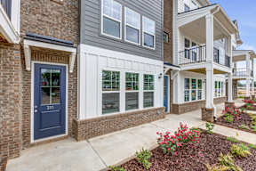 Townhome entrance with brick accents and white siding at The Courts at Maverick Yards Apartments, Mauldin