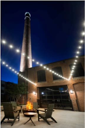 Cotton Mill Apartments outside chairs and fire pit with chimney at night, lit up by string lights