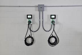 Two electric vehicle charging stations are installed on a white wall.