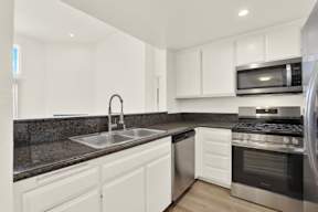 A modern kitchen with white cabinets and stainless steel appliances.