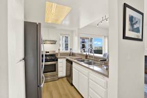 A kitchen with a refrigerator, sink, and cabinets.