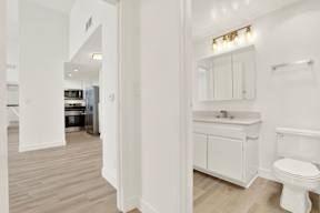 A white bathroom with a toilet, sink, and cabinet.
