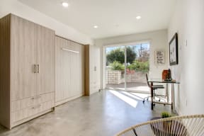 a home office with a desk and a sliding glass door leading to a patio