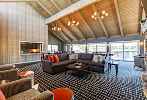 Clubhouse at Somerset Lakes Apartments, featuring a large open living room with a fireplace and a balcony for relaxation.