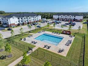 A pool surrounded by a black fence and lawn chairs.