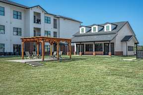 A white building with a wooden pergola in front of it.