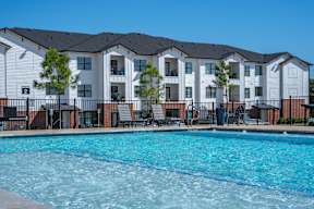 A large swimming pool in front of apartment buildings.