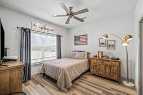 A bedroom with a bed, nightstand, and a ceiling fan.
